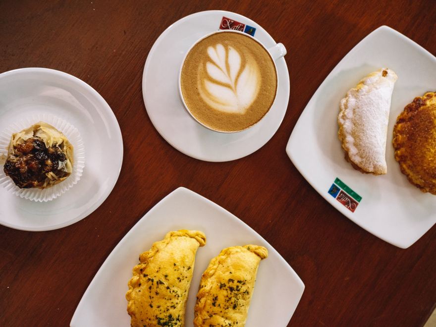 Las empanaditas ya horneadas, servidas en la mesa con un capuchino