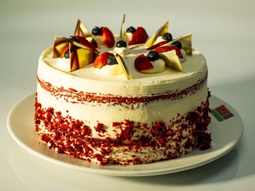 Torta red velvet entera, decorada con fresas, arándanos y chocolate blanco