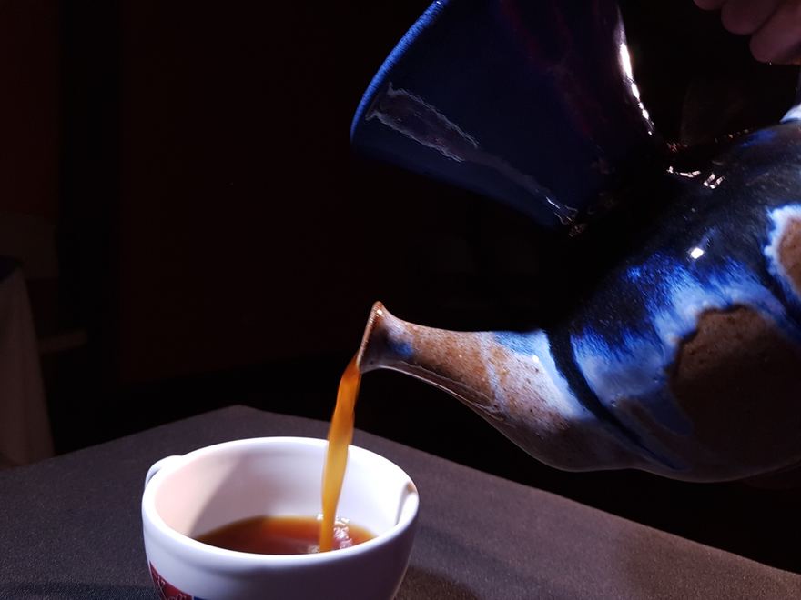 Una vandola de barro sirviendo café en la taza
